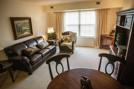 A cozy living room featuring a comfortable sofa, a wooden table, and natural light streaming through the window.