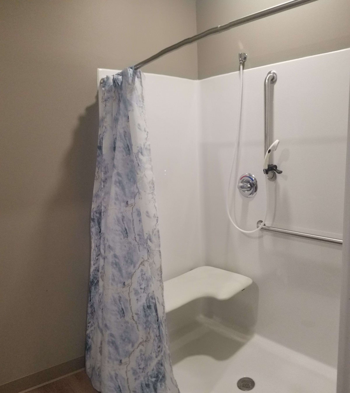 Accessible shower with curtain and handrail.