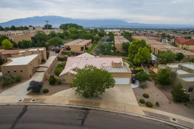 A suburban neighborhood with houses, trees, and distant mountains in the background.