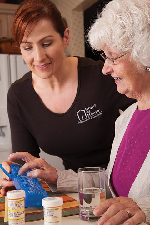 A caregiver assisting an elderly woman with using a tablet.