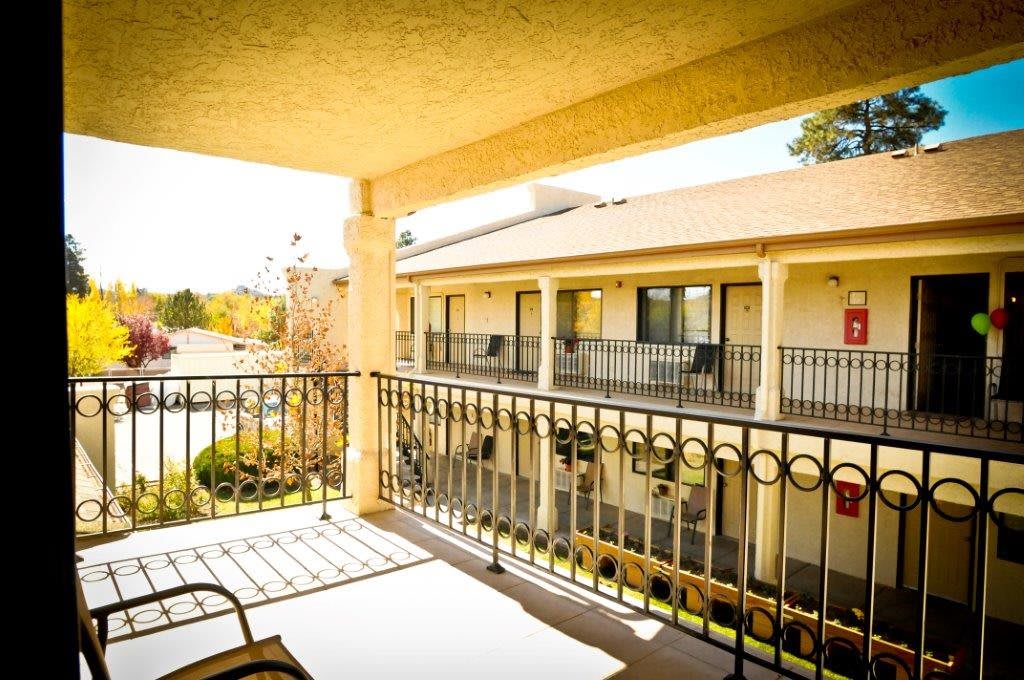 A sunny view from a hotel balcony overlooking neighboring rooms.