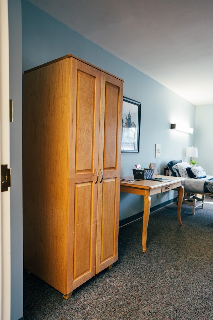 A cozy room interior featuring a wooden wardrobe and a table beside a sofa.