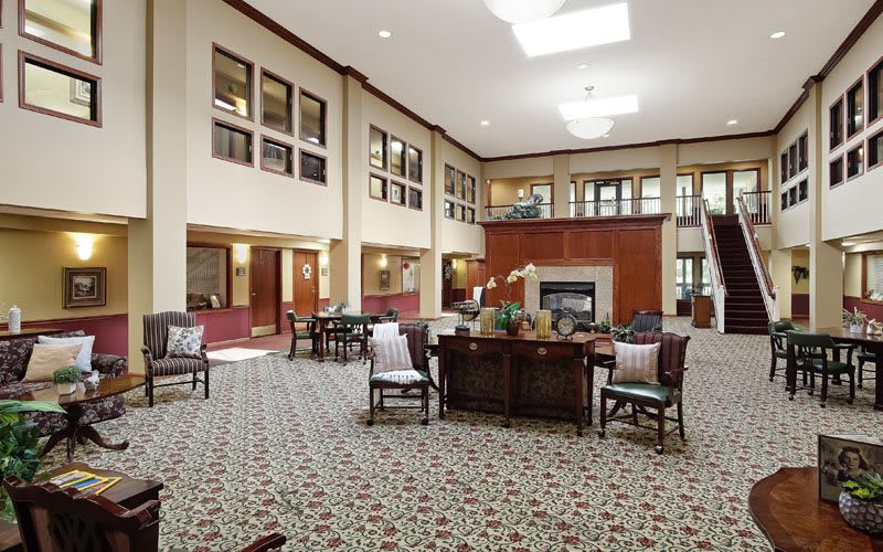 A spacious and modern lobby featuring comfortable seating, a central fireplace, and ample natural lighting.