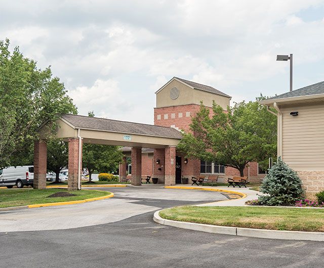 A building with a covered driveway entrance surrounded by trees on a cloudy day.