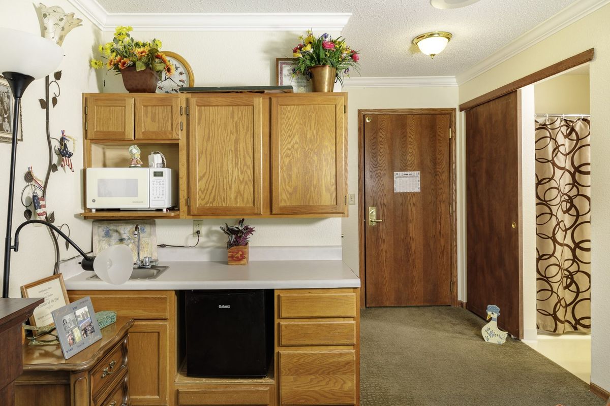 A cozy kitchen with wooden cabinets, a microwave, and decorative plants.