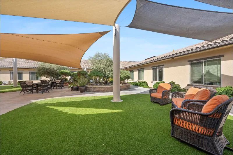 A sunny backyard with shade sails and comfortable patio furniture.