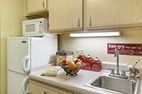 A kitchen counter with a microwave, sink, and fruit bowl.