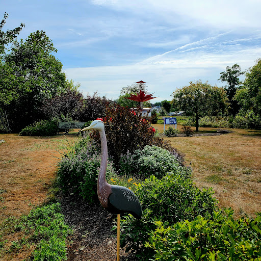 A serene garden scene featuring a decorative sculpture amidst lush greenery and a clear sky.