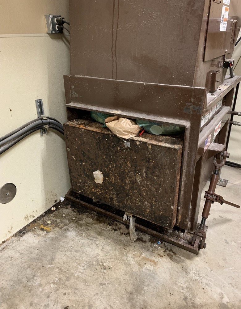 An industrial trash compactor with waste material inside.