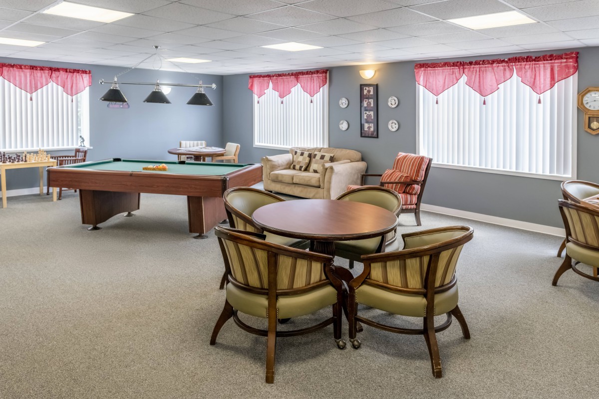A cozy game room featuring a billiards table and a seating area with comfortable chairs.