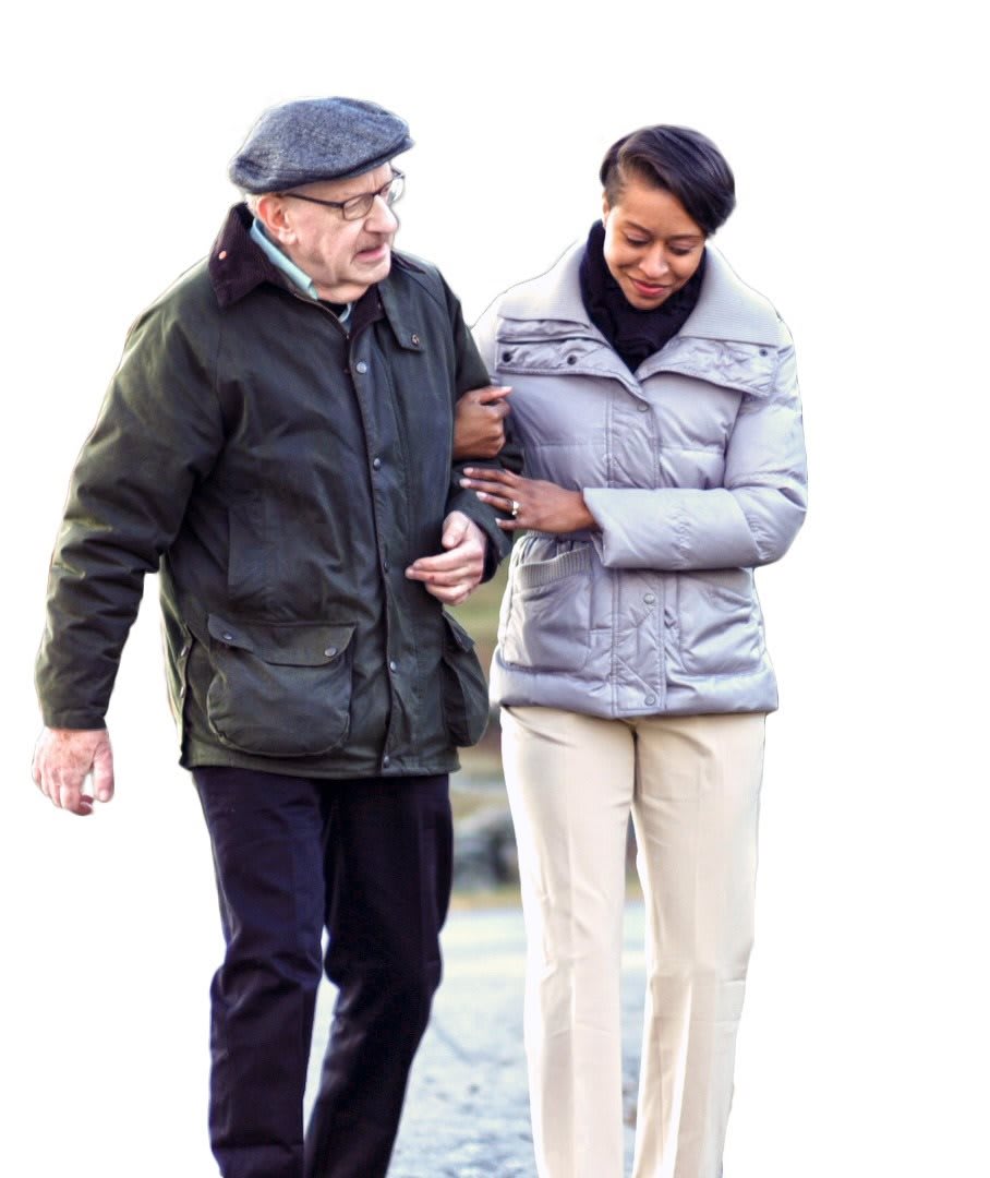An elderly man is being assisted while walking outdoors.