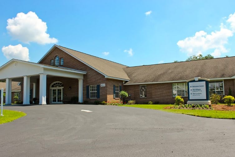 A brick building with a gabled roof and adjacent parking area under a clear blue sky.