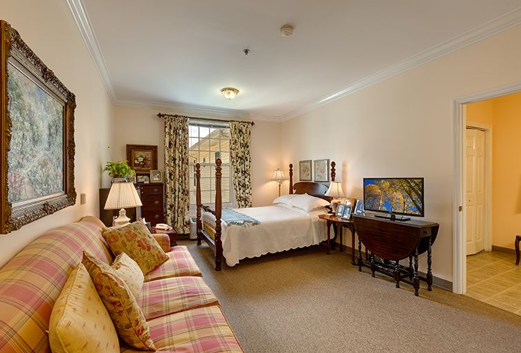 A cozy bedroom with a bed, sofa, and television, decorated warmly.