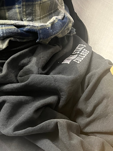 A close-up view of folded clothing, featuring a black shirt and a plaid garment.