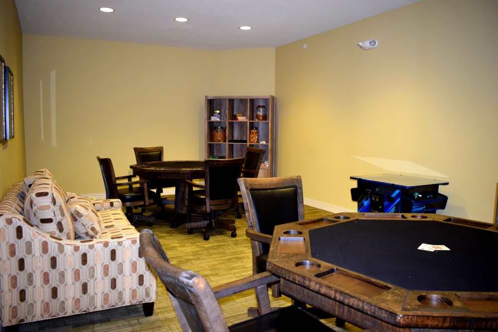A cozy game room with a poker table, comfortable seating, and shelves for storage.