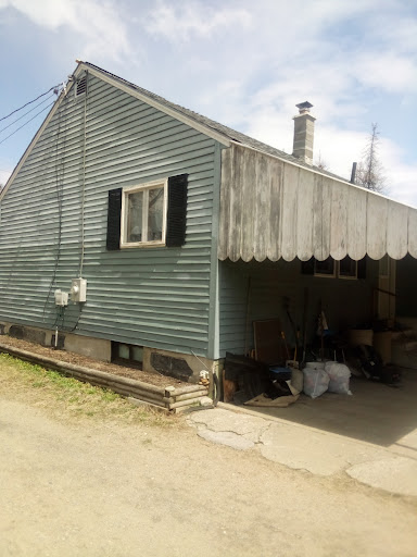 A quaint green house with a garage and an awning.