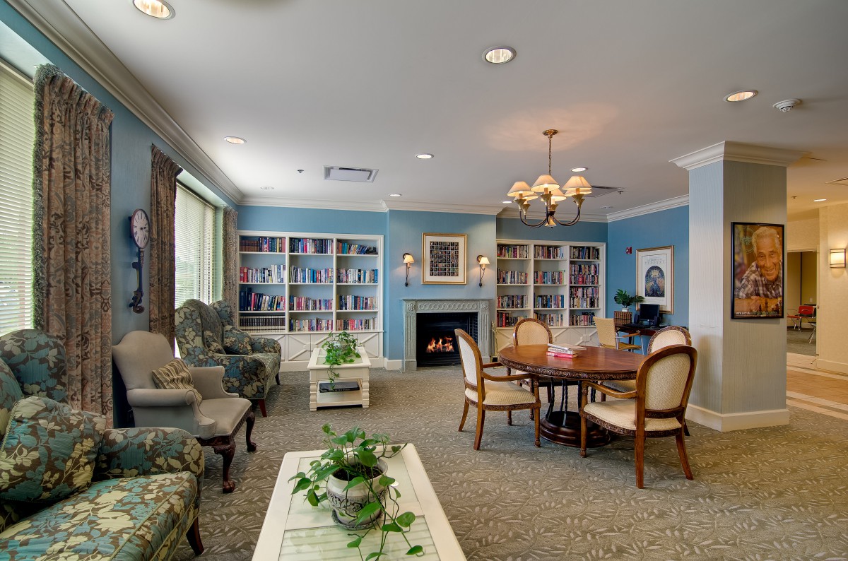 A cozy living room with a library corner, featuring comfortable seating, bookshelves, and a fireplace.
