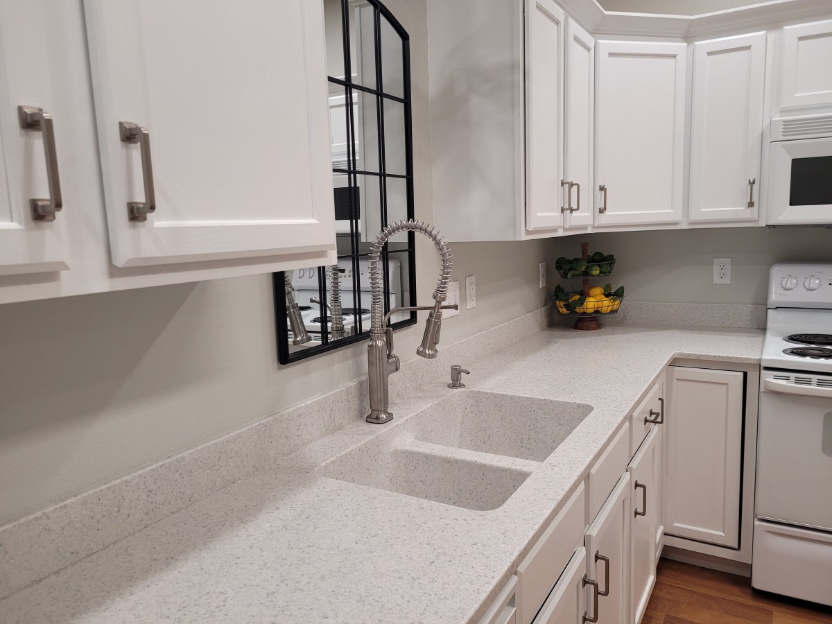 A modern kitchen with white cabinets and countertop.
