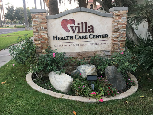 Welcome sign of Villa Health Care Center surrounded by a landscaped garden.