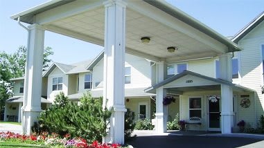 A residential building entrance with a covered porch and landscaping.