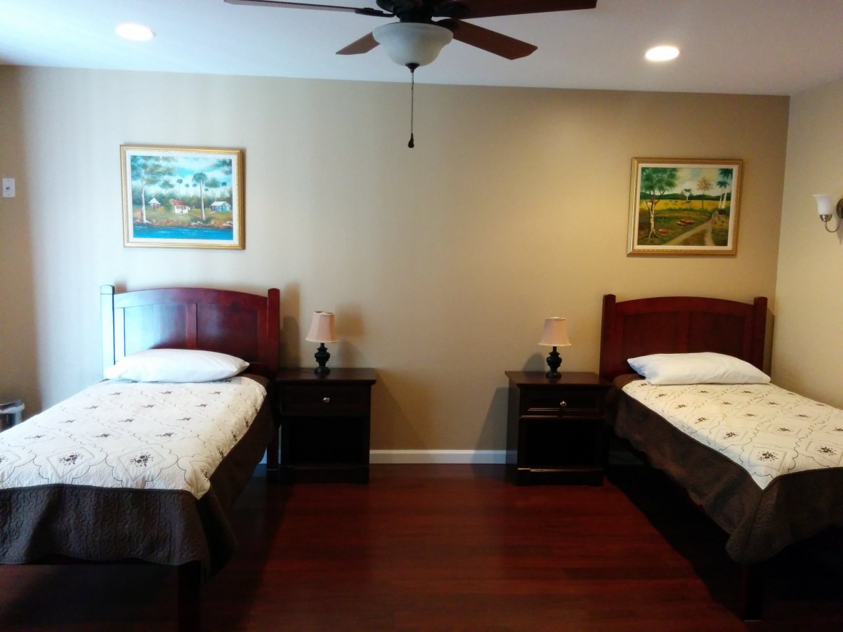 A neatly arranged bedroom featuring twin beds, nightstands, and wall art.