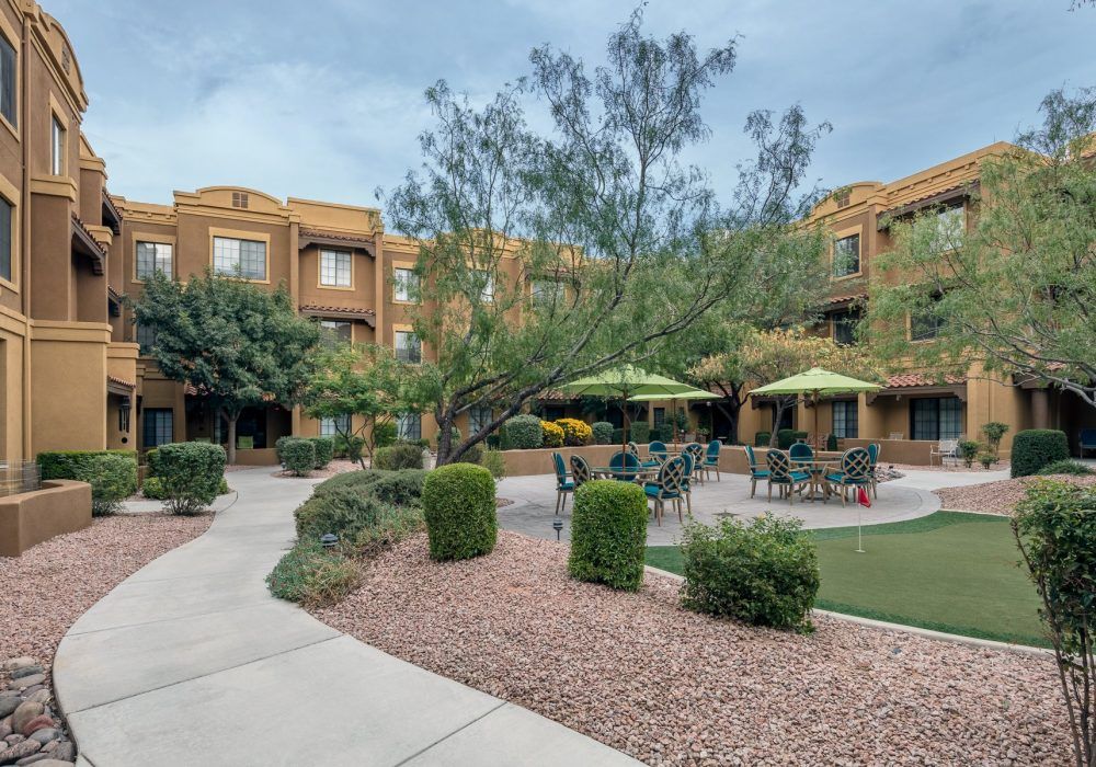 A well-maintained courtyard with outdoor seating and lush landscaping in an apartment complex.