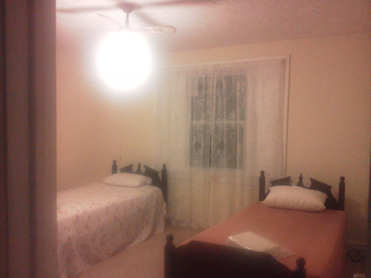 A cozy bedroom with two single beds and a window adorned with curtains.