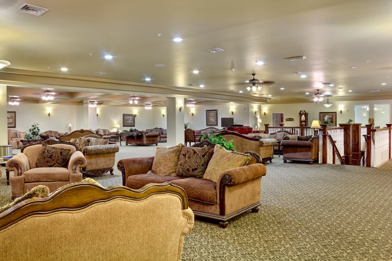 A spacious lounge area with multiple sofas and tables, warmly lit by ceiling lights.