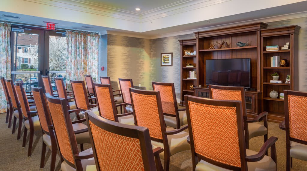 A small conference room with arranged chairs facing a television and bookshelf.