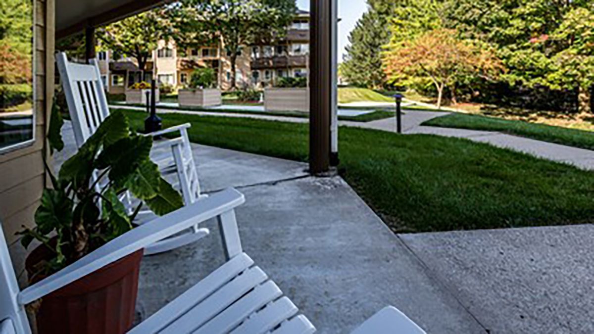 A peaceful garden patio area with benches and a view of an apartment complex.