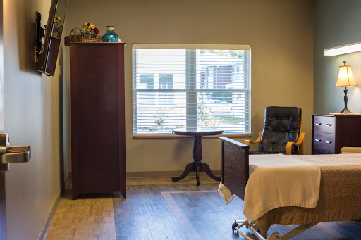 A cozy room featuring a bed, chair, wardrobe, and a window that allows natural light to fill the space.