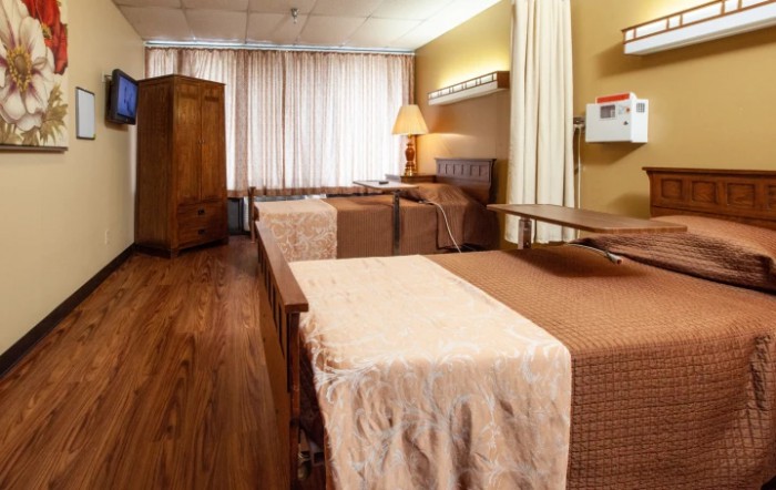A cozy hospital room with two beds and a warm wooden interior.