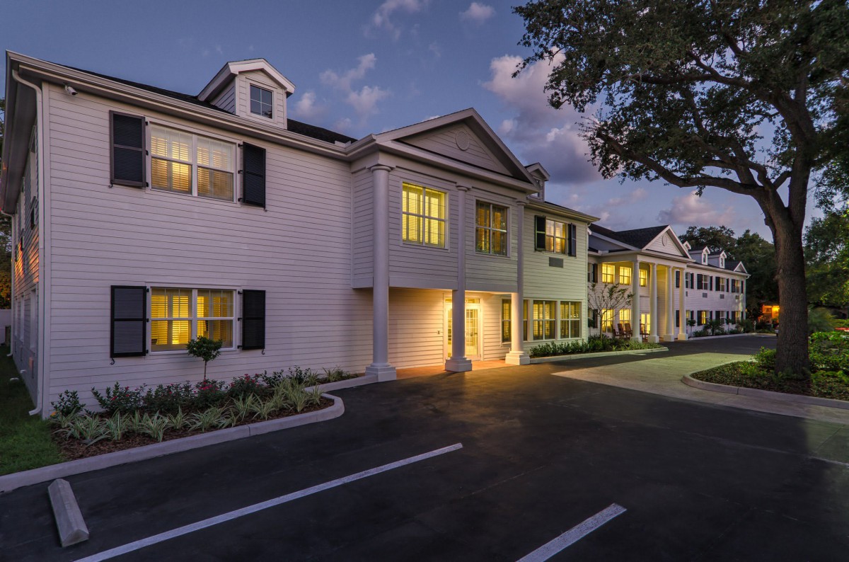 A nighttime view of a well-lit residential building with a parking lot.