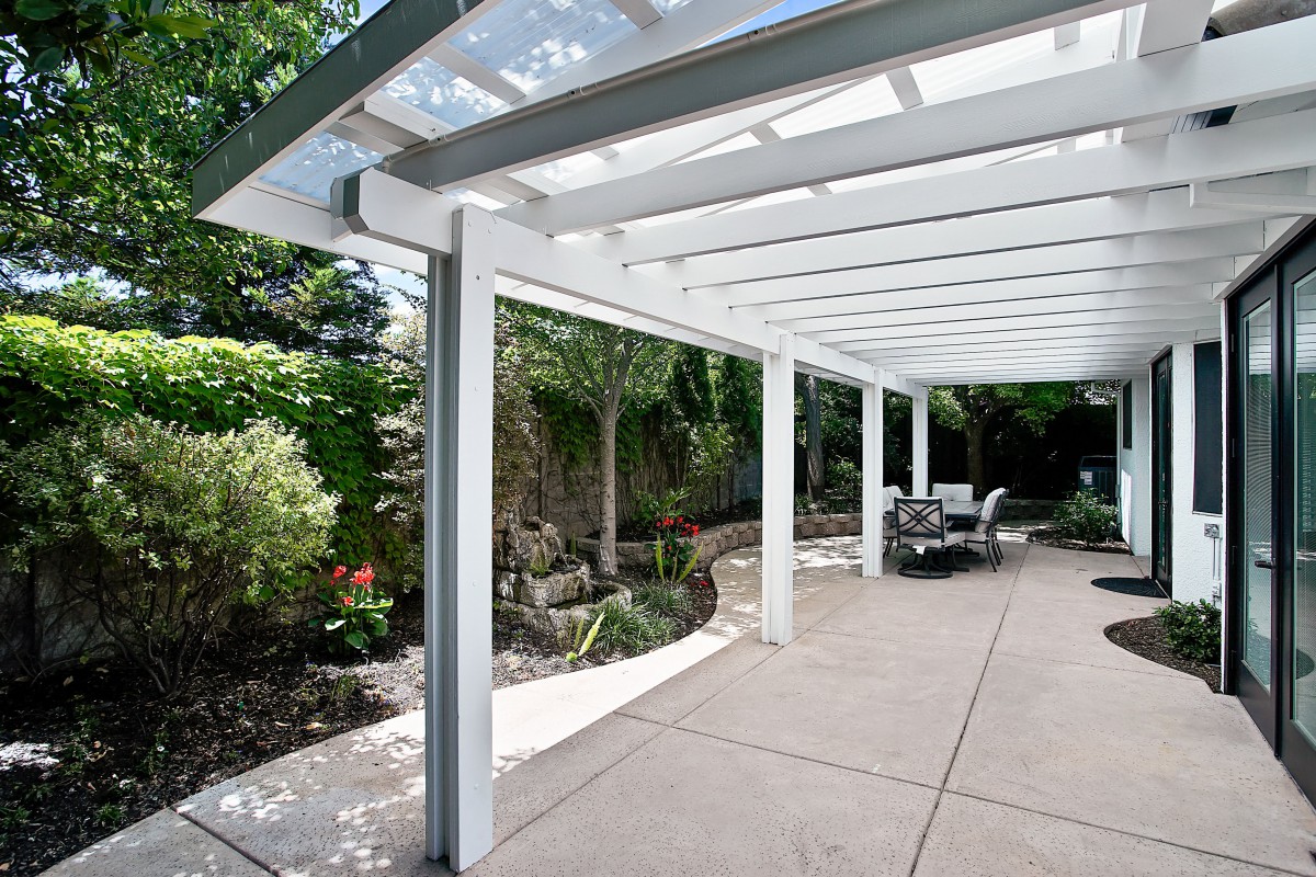 Modern pergola-covered patio with outdoor seating amidst lush garden landscaping.