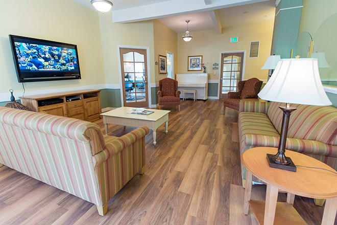 A cozy living room with seating arrangements, a television, and wood flooring.