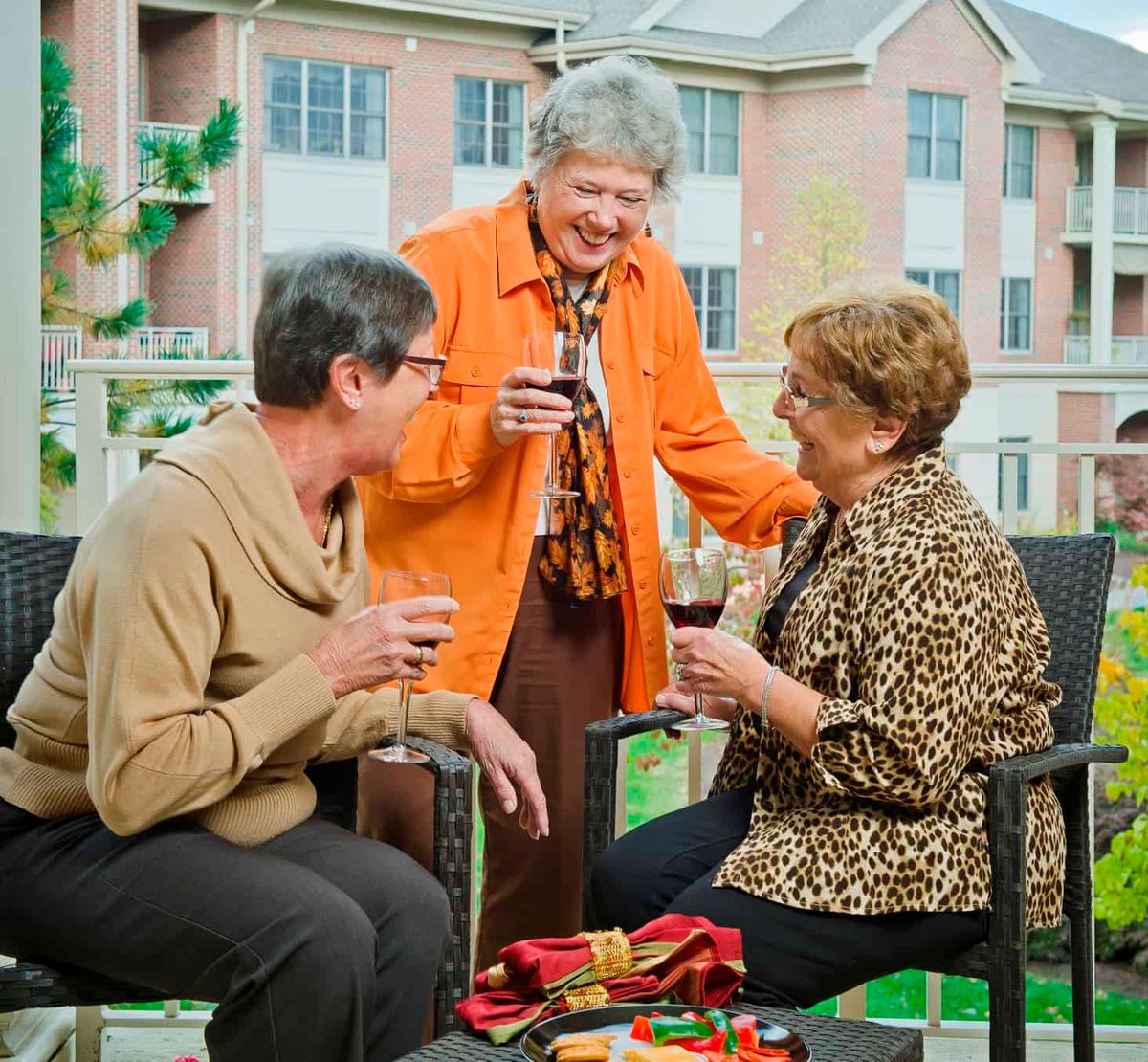 Three elderly women enjoying drinks and conversation outside.