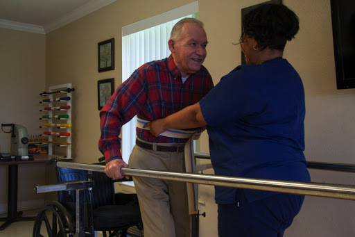 A caregiver assists an elderly man during a physical therapy session, promoting mobility and independence.