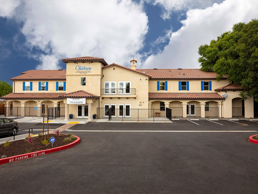 A hotel building with a clear sky backdrop and an empty parking lot in front.