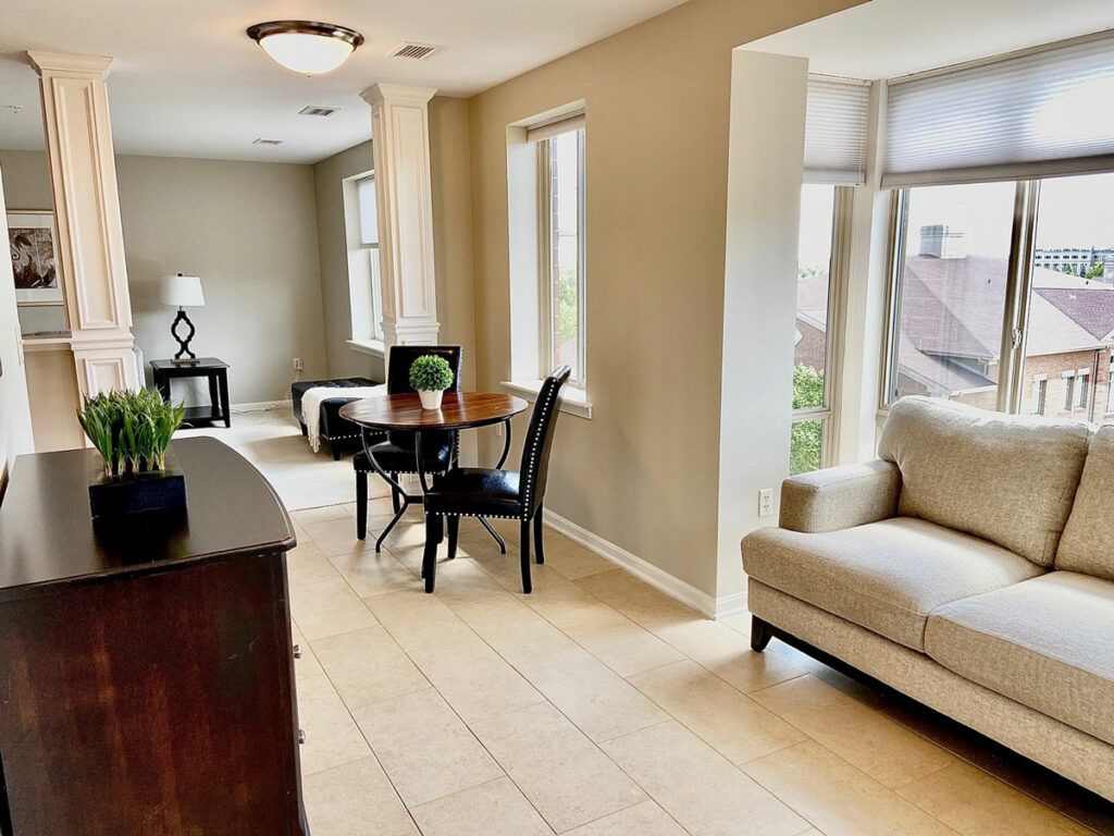 A modern living room with natural light, featuring a sofa and dining area.