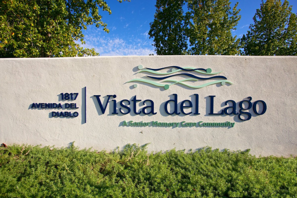 Entrance sign for Vista del Lago community surrounded by greenery.
