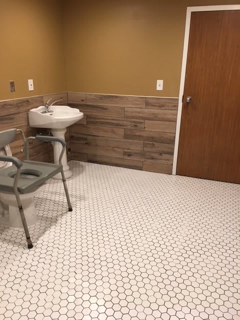 A simple bathroom with a sink, chair, and tiled floor.