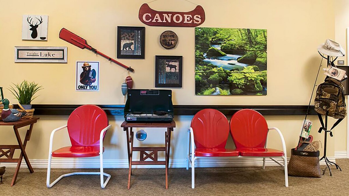 A canoe-themed waiting area with red chairs, nature artwork, and a small computer station.