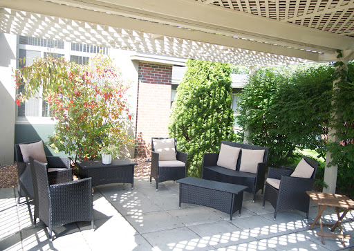 A cozy outdoor patio area featuring modern seating and lush greenery.