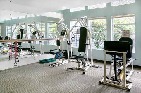 A gym with workout machines and large windows.