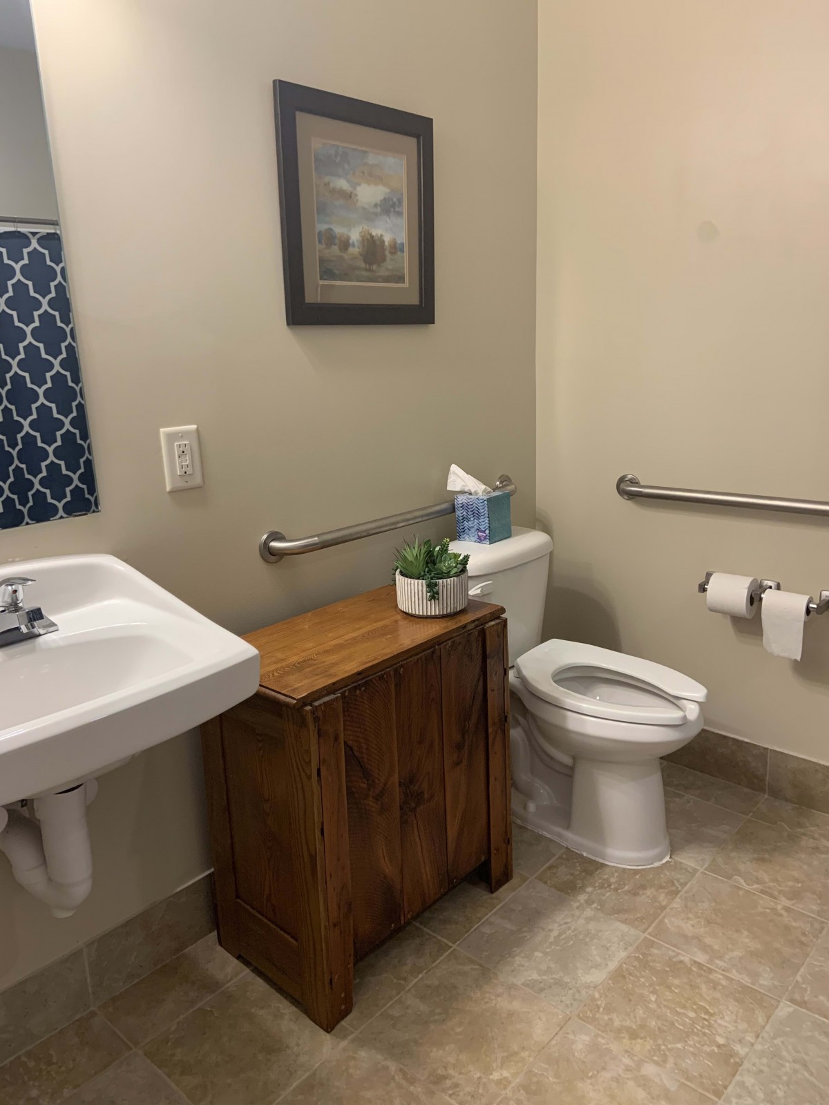 A bathroom with a sink, toilet, and wooden cabinet.