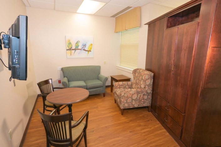A comfortable waiting room with seating and a small table, featuring a painting on the wall.