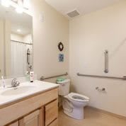 Accessible bathroom with a toilet, sink, and safety grab bars.