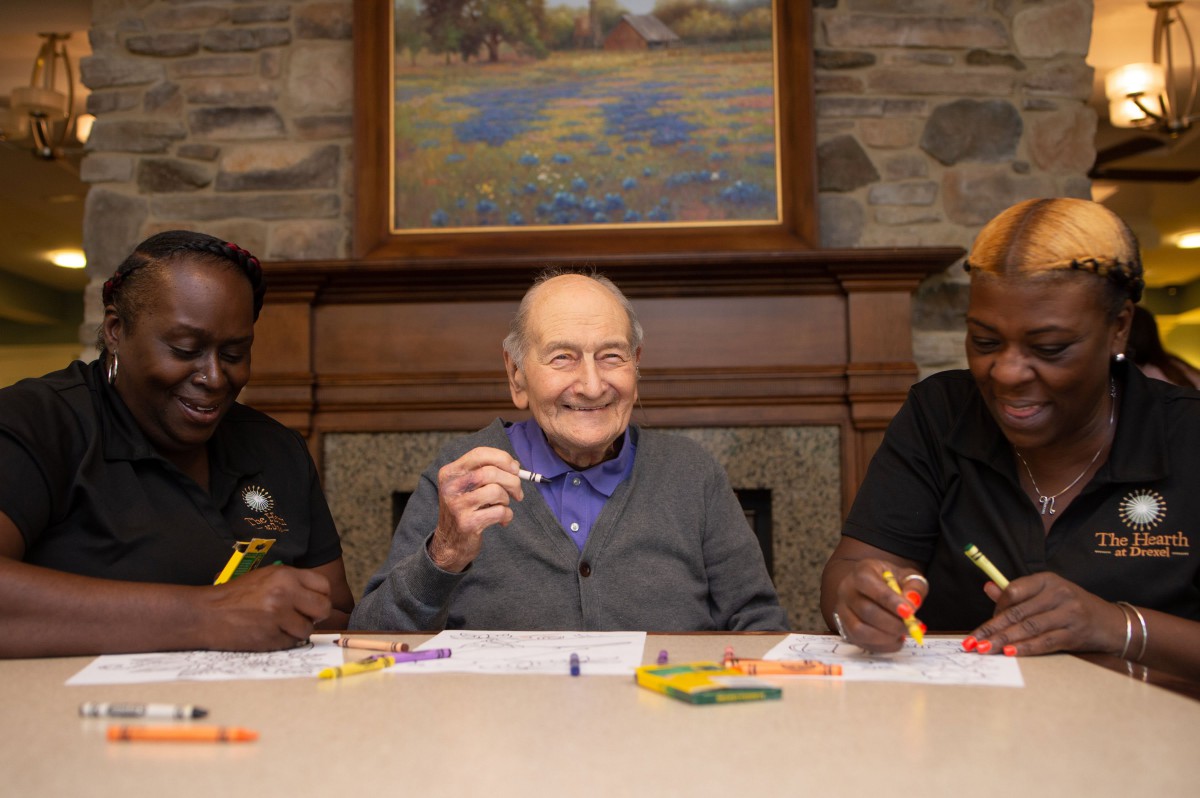 A group of people engaged in a coloring activity, sharing smiles and creativity together.