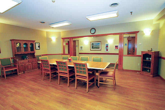 A well-lit conference room with a large wooden table and chairs arranged around it.