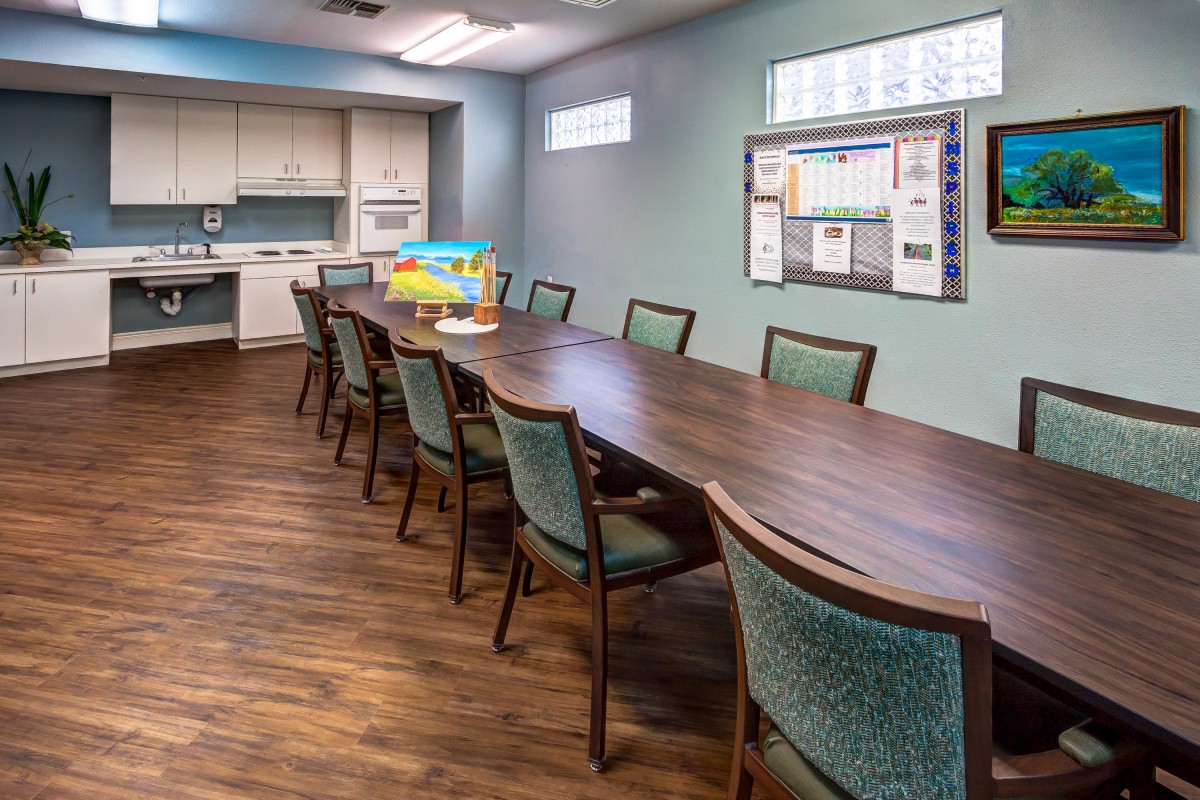 A modern conference room with a large meeting table and kitchenette.